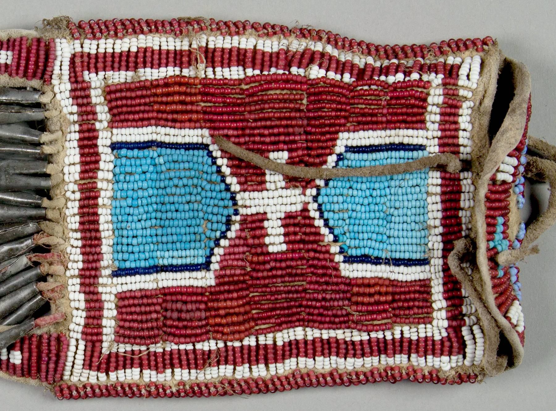 A strike a light bag from NMNH. Its background is beaded with red white inside seed beads. At the upper part of the picture, the white centers are revealed.